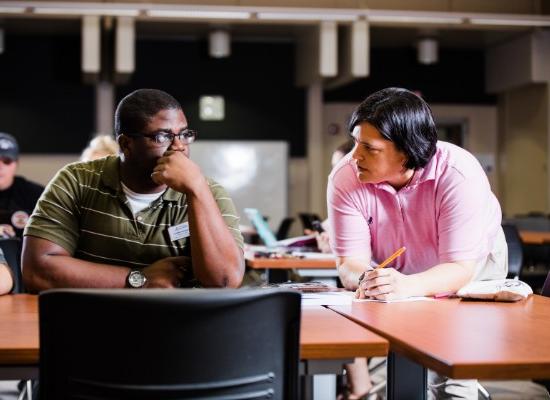 Education professor assisting student in the classroom.